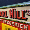 Carl Nill’s Spitzenwegerich Brustbonbons (Geprägtes Blechschild um 1905)