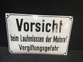 Vorsicht beim Laufenlassen der Motore! Vergiftungsgefahr (Gewölbtes Emailleschild um 1950)