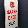 Haake Beck Glaswerbeschild im Rahmen (50er Jahre) - Variante 3 mit S im Schreibschriftstil (enger Schwungbogen)